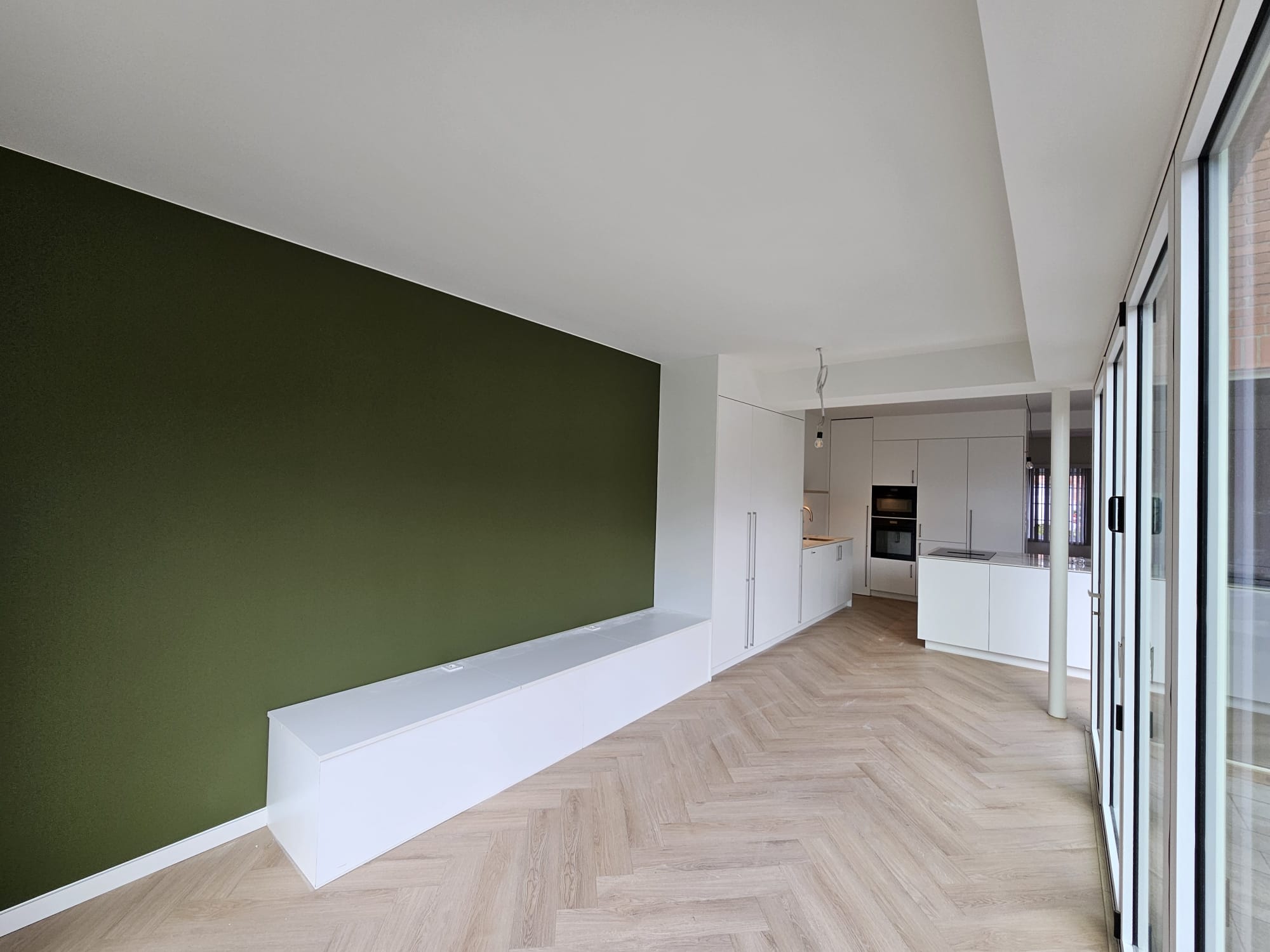 Na: strak geschilderde woonruimte met diepgroene accentwand en wit plafond